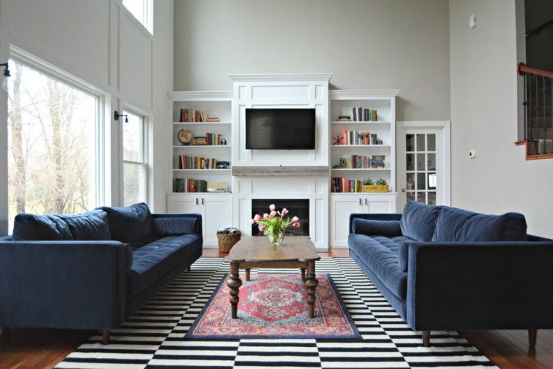 Inside a living room with two couches on each end, a table in the middle, and a TV attached to the wall.