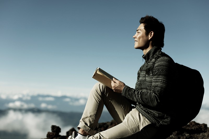 Young man reading a book in the mountains