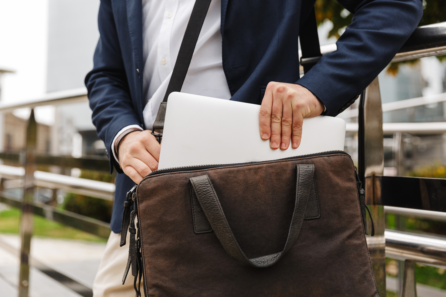 Man slipping a folder inside his laptop bag.