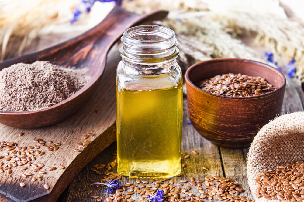 Flaxseed oil in a bottle near flaxseed on a wooden table.