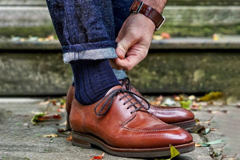 A man folding the hem of his pants to show his dress socks.