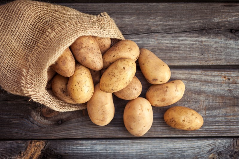 A sack of potatoes on a wooden table.