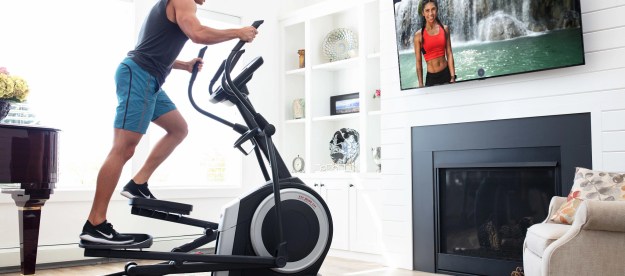 A man working out on the ProForm Carbon EL Elliptical while watching TV.