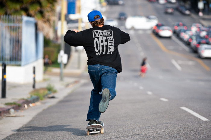 Kid skating down the street in Vans