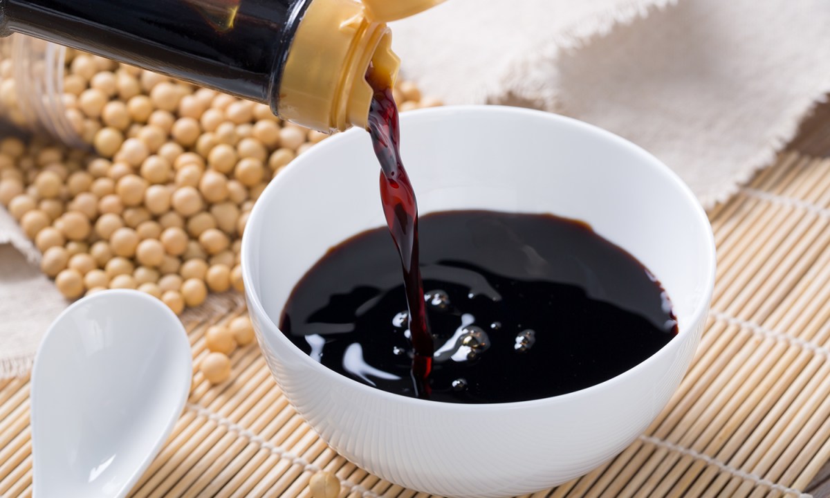 Pouring soy sauce into a white bowl