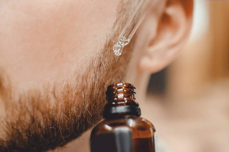 Bearded man applying a product on his face.