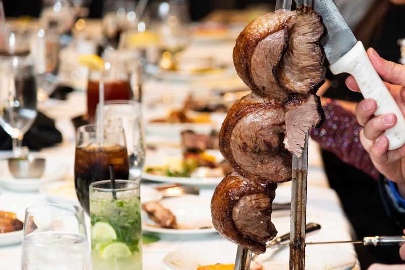 Brazilian Barbecue or churrascaria being cut down to serve at a dinner party.