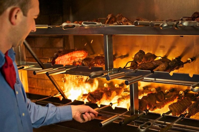 Man cooking and rolling the meat to cook it evenly.
