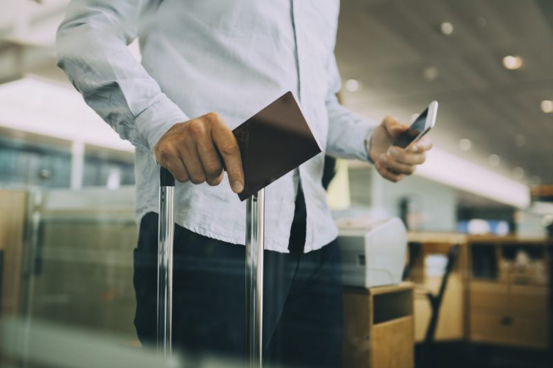 Person holding passport and luggage at the airport.