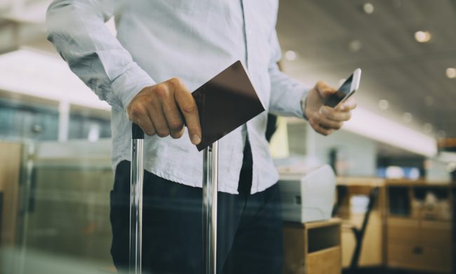 Person holding passport and luggage at the airport.