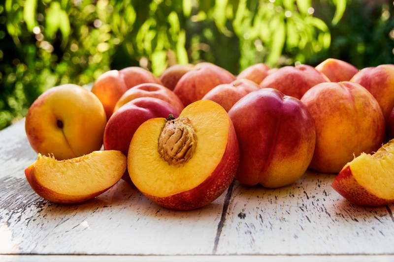 Ripe peaches with leaves on the old wooden table