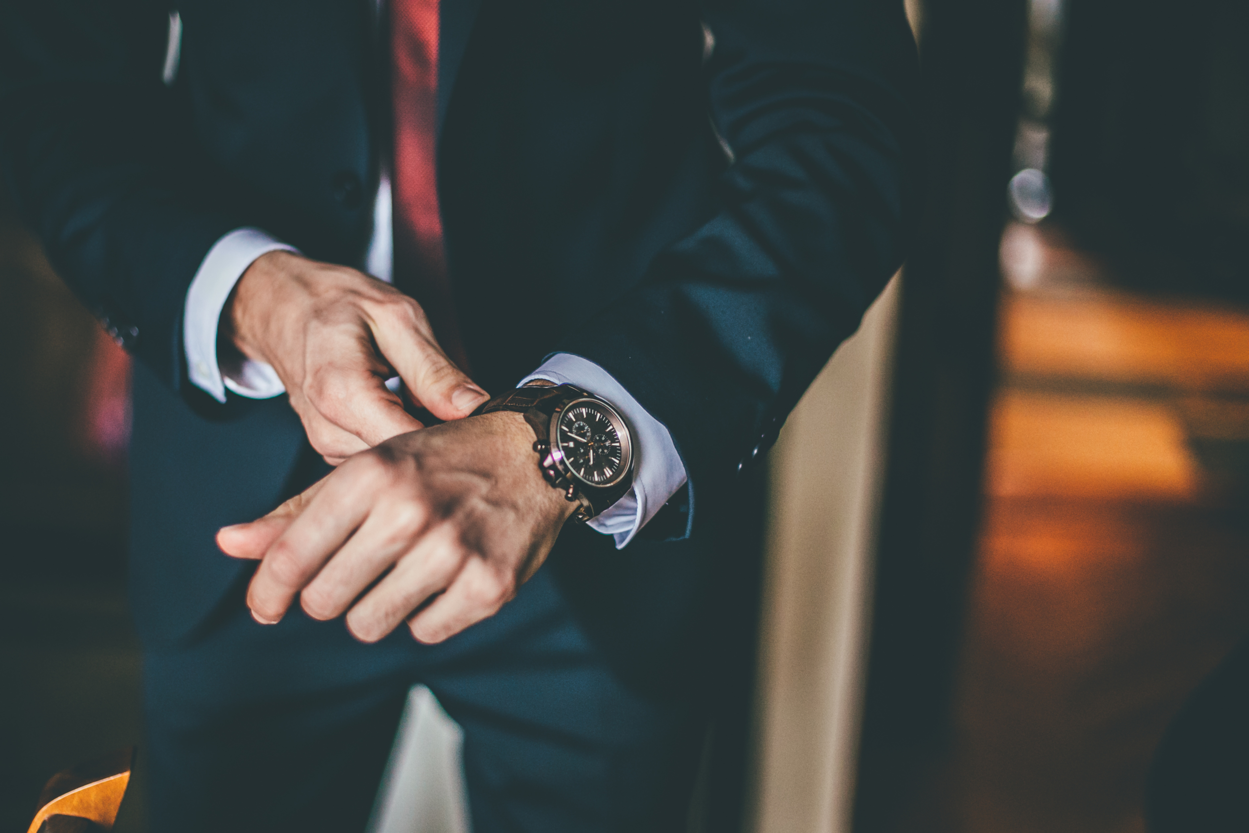 Man in a suit adjusting the band of his wristwatch.