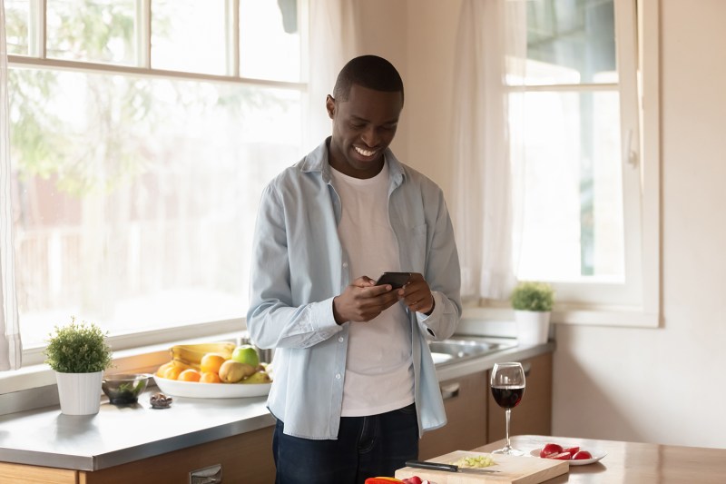 man using smart phone in kitchen