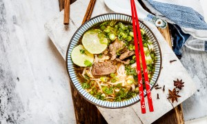 Bowl of Vietnamese Pho with rice noodles, mung beans, cilantro, spring onions and limes