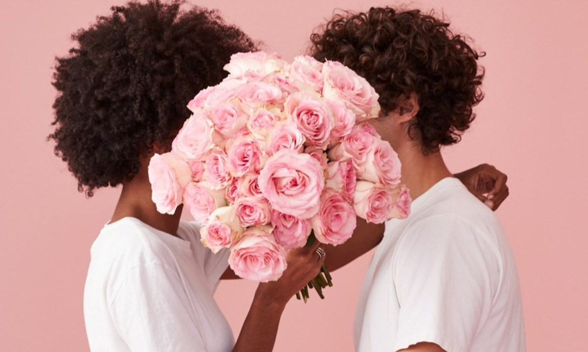 A couple kissing with a bouquet of flowers in front of them
