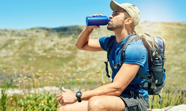 Taking a break from hiking to drink some water from an insulated water bottle