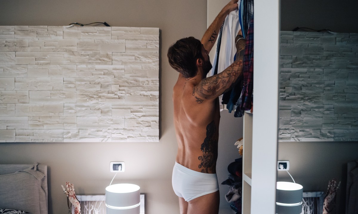 Man in underwear getting dressed in a bedroom