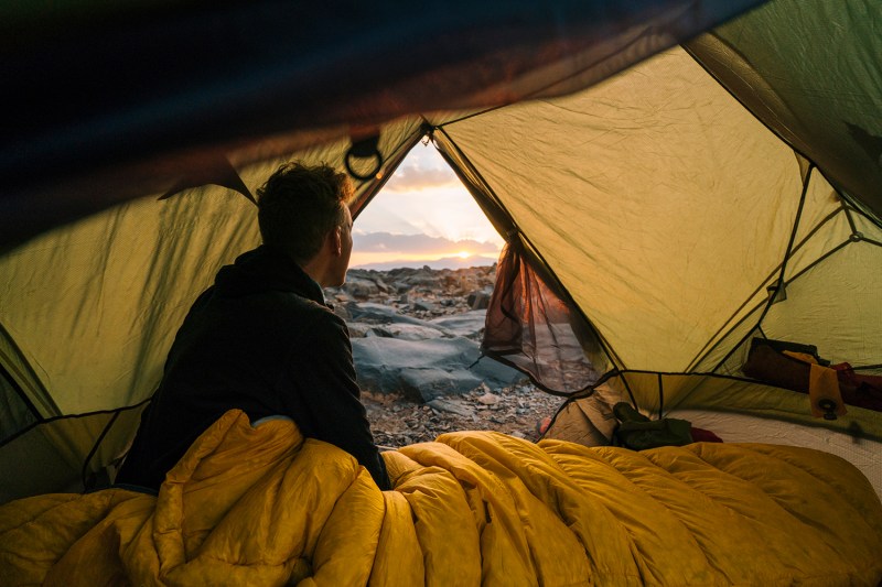 Camping with a view out of his tent door in a sleeping bag