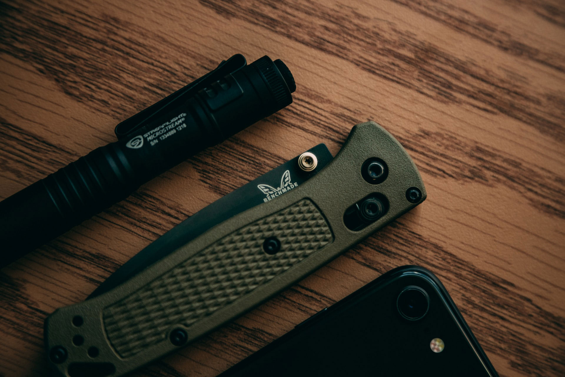 Overhead view of everyday carry items, including a penlight, pocket knife, and smartphone