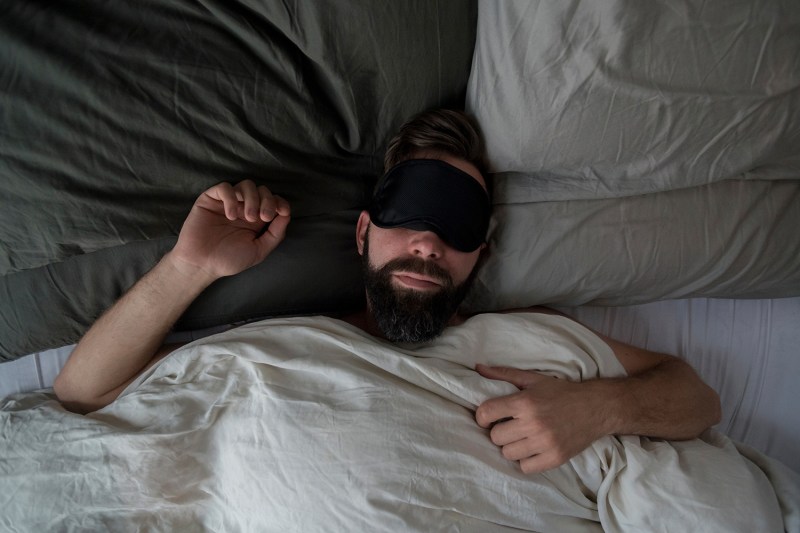 Man in a bed with a sleep mask.