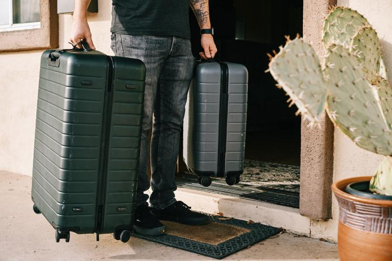Man carrying two hard-sided suitcases.