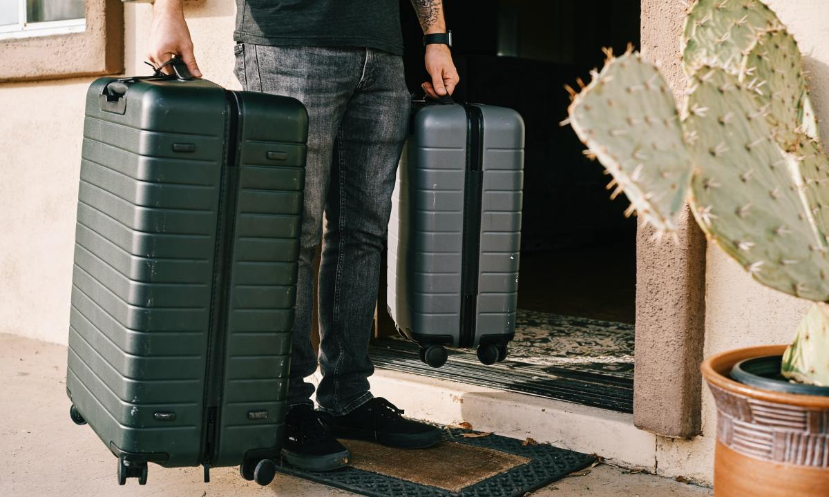 Man carrying a suitcase and carry-on suitcase