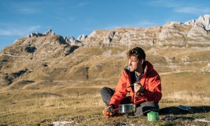 best mres backpacker prepares meal on camp stove in mountains