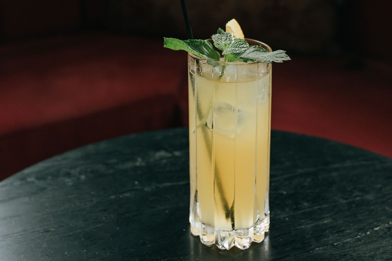 A glass of Veracruz Smash Cocktail with mint sprig and straw on a table.