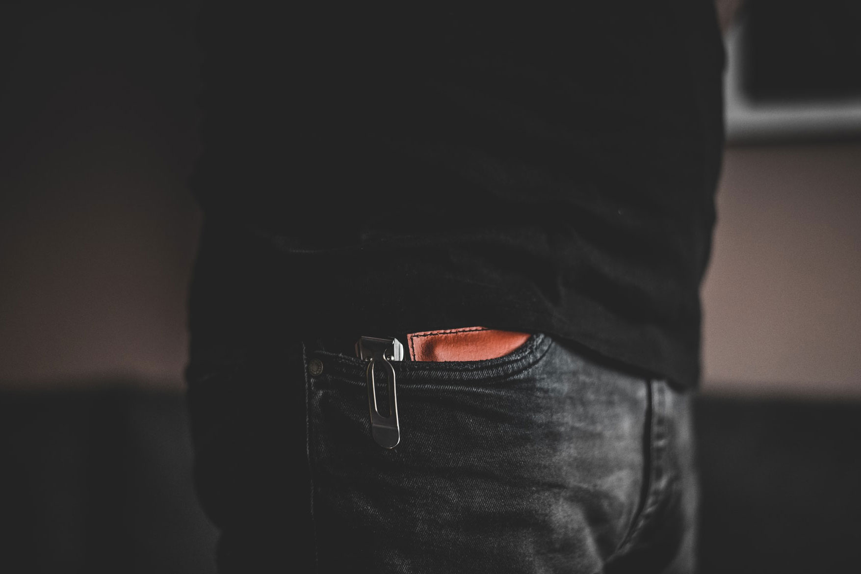 Close-up of a pocket knife and wallet peeking out of the pocket of someone's jeans