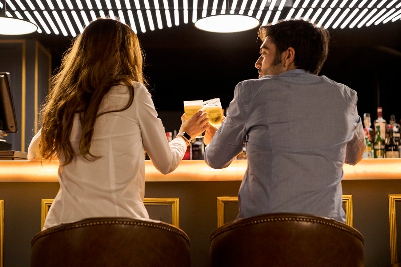 Rear view of couple clinking beer glasses in a bar