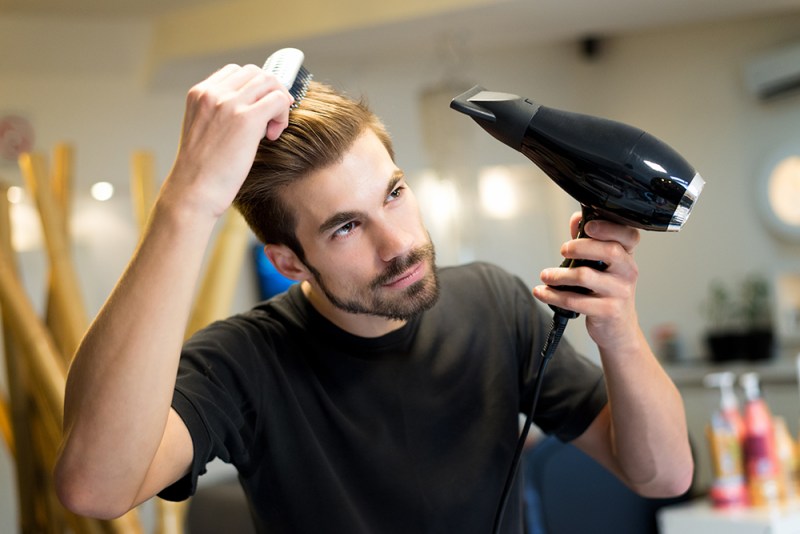 A person drying their hair using a hair dryer.