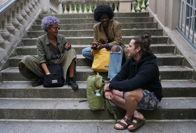 Three people sitting on stairs talking