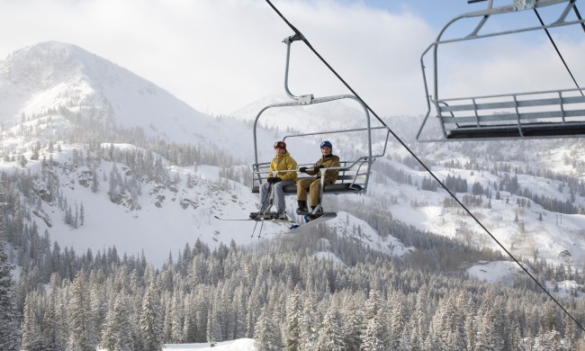 Snowboarder and skier sitting on ski lift at Brighton ski resort