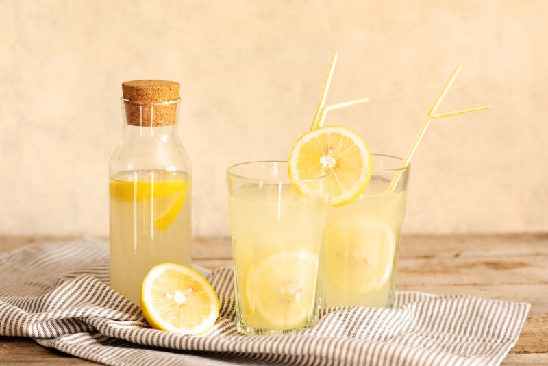 Jar of tasty fresh lemonade with lemons in background