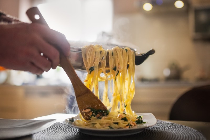 Cooked pasta being spooned onto a dish