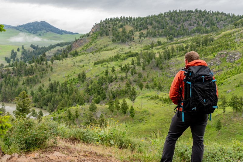 Man with pack looks out over Yellowstone wilderness on overcast day