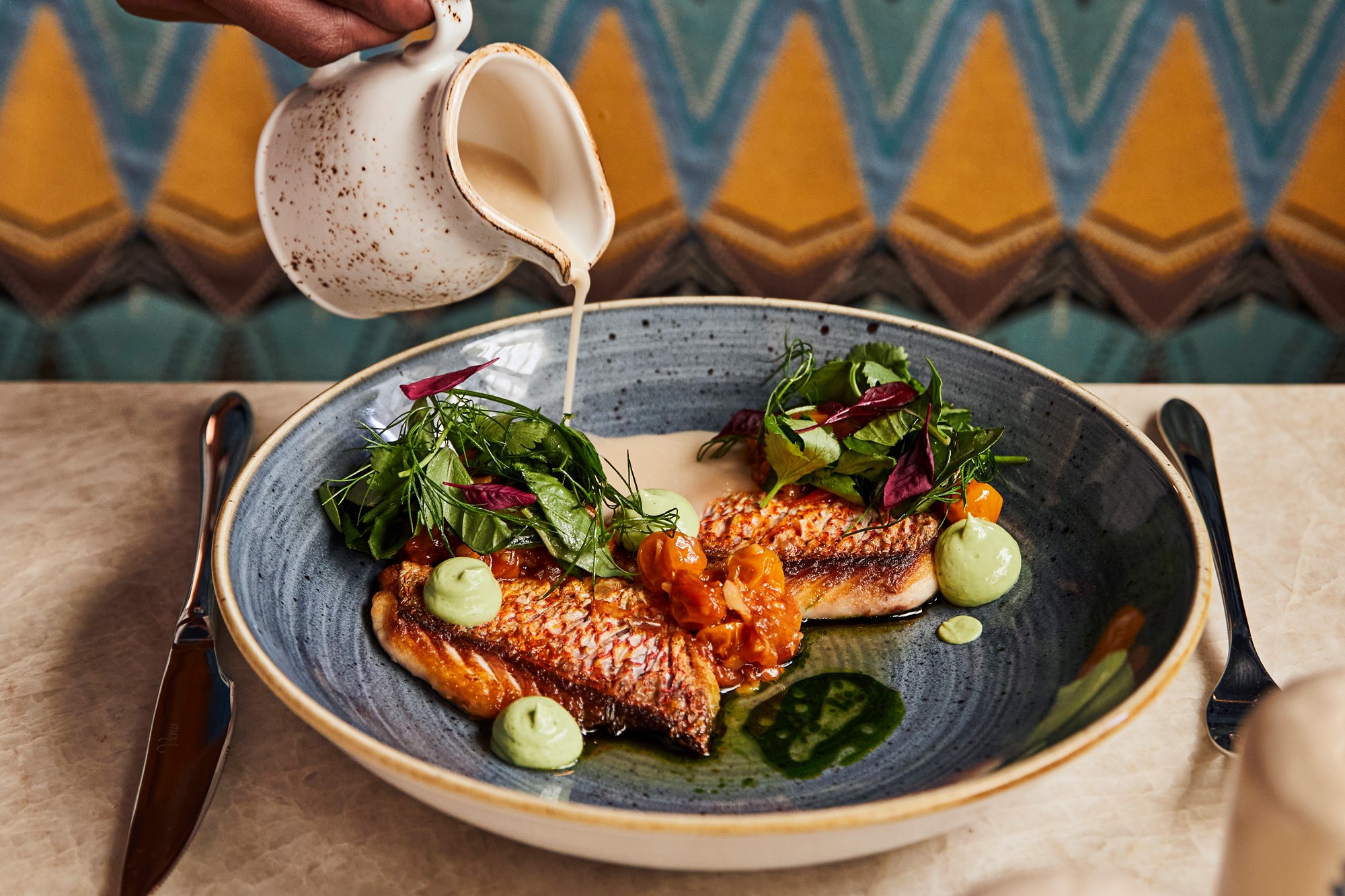 Sauce poured over grilled fish at Red Rooster Overtown