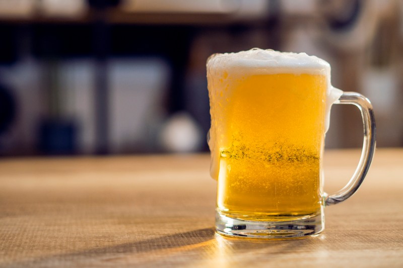 A glass filled with crystal clear, straw yellow pilsner sitting on a table.