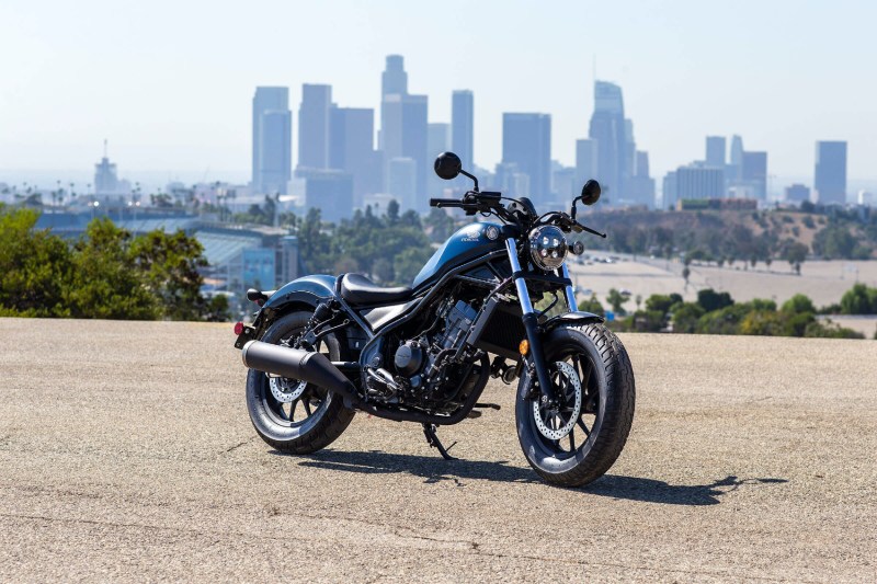 Honda Rebel 300 in front of a city skyline on a paved road.