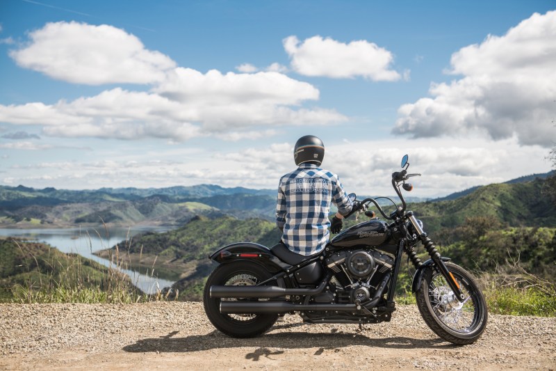 Motorcycle rider looking at mountain range on the side of a dirt path.