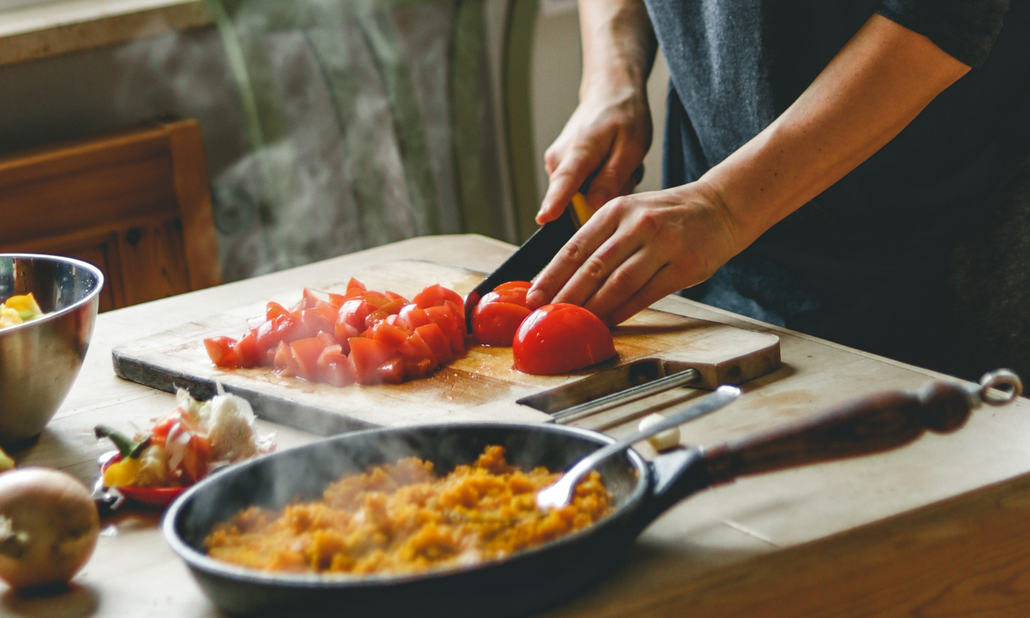 A person cutting up tomatoes for a healthy meal