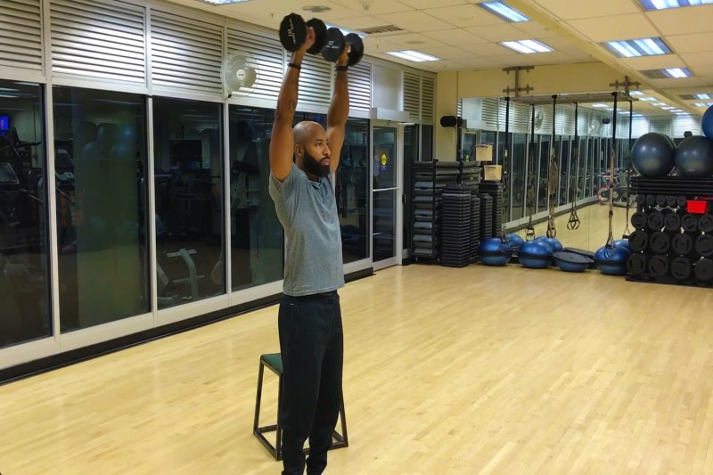 Man raising the dumbbells on each hand above his head.