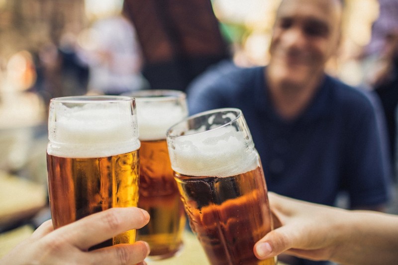 Three friends cheering with glasses of pilsner beer
