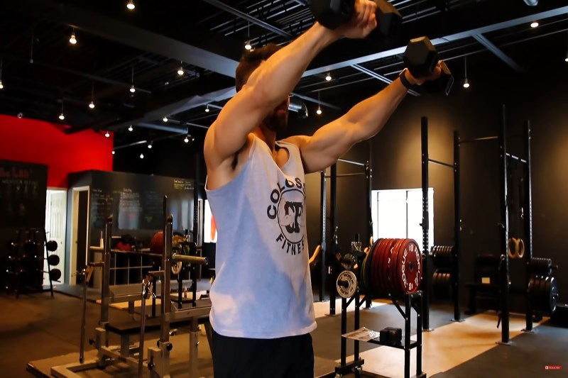 Man holding a dumbbell in each hand raising his arms out in front of him until they are parallel to the floor.
