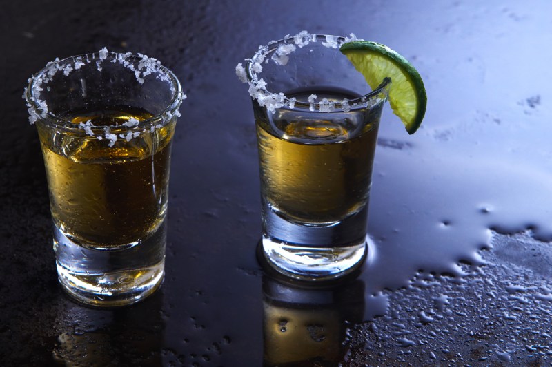 Two shot glasses rimmed with salt and a lime wedge