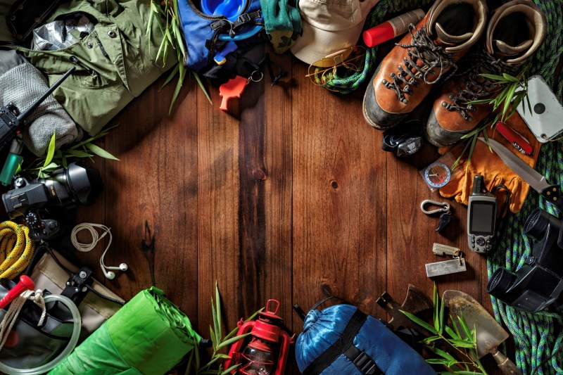 Overhead shot of hiking gear laid out in a circle on a wood surface.