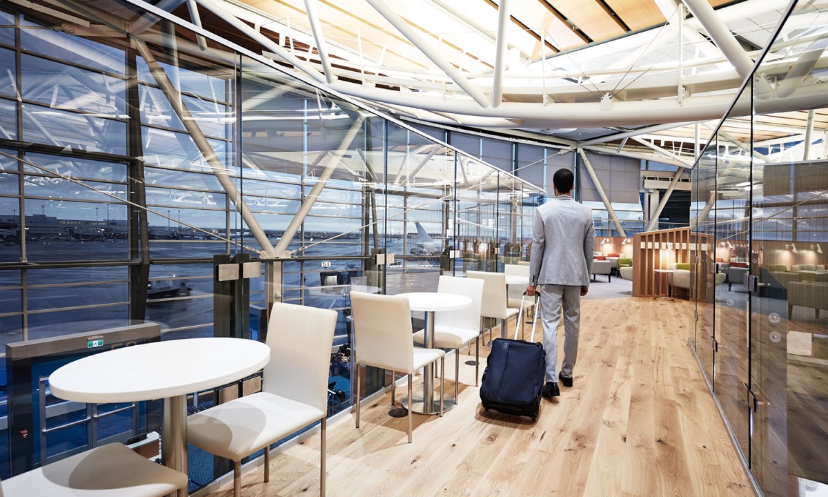 Man wheeling a rollaboard suitcase through a Priority Pass lounge in the Vancouver Airport