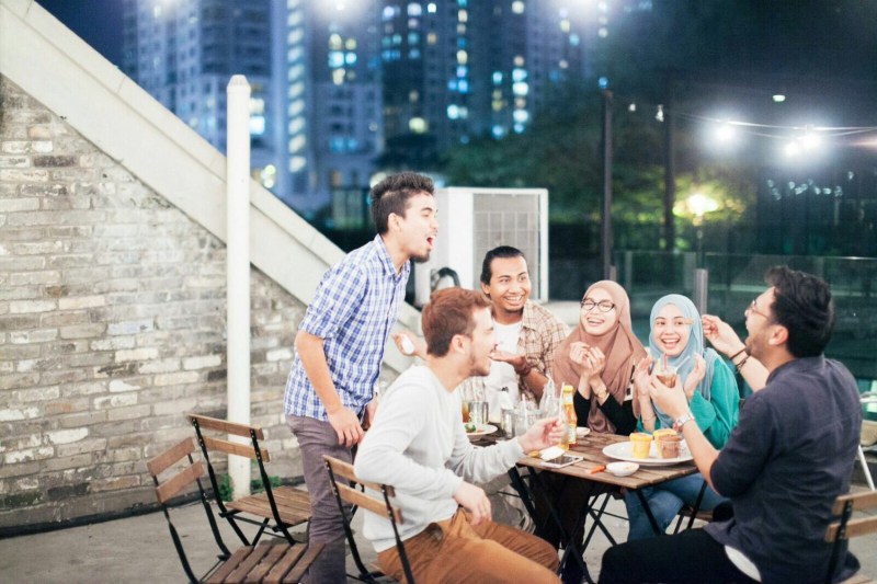 Group of friends sitting around a table at night on the rooftop