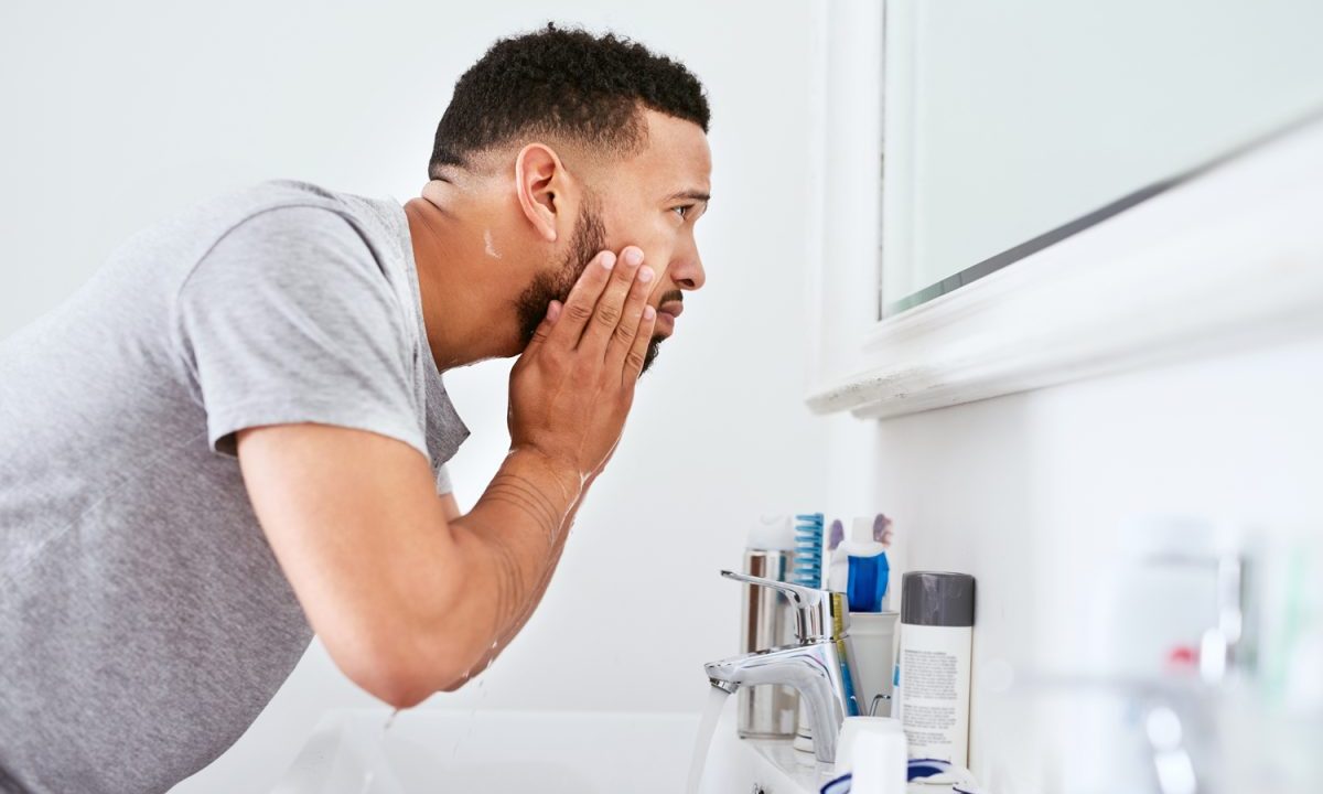 Man looking in the mirror applying skincare products
