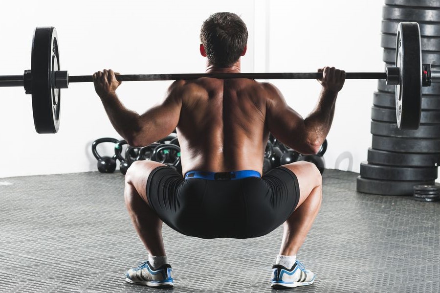 Man doing sumo squats with a barbell